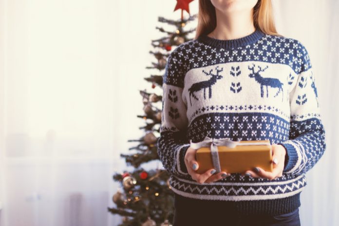 Pige har julesweater på og giver gave