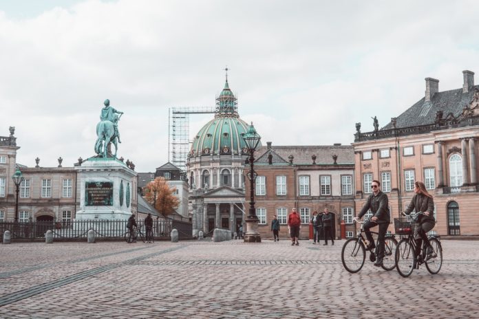 Person cykler forbi statue inde i københavn